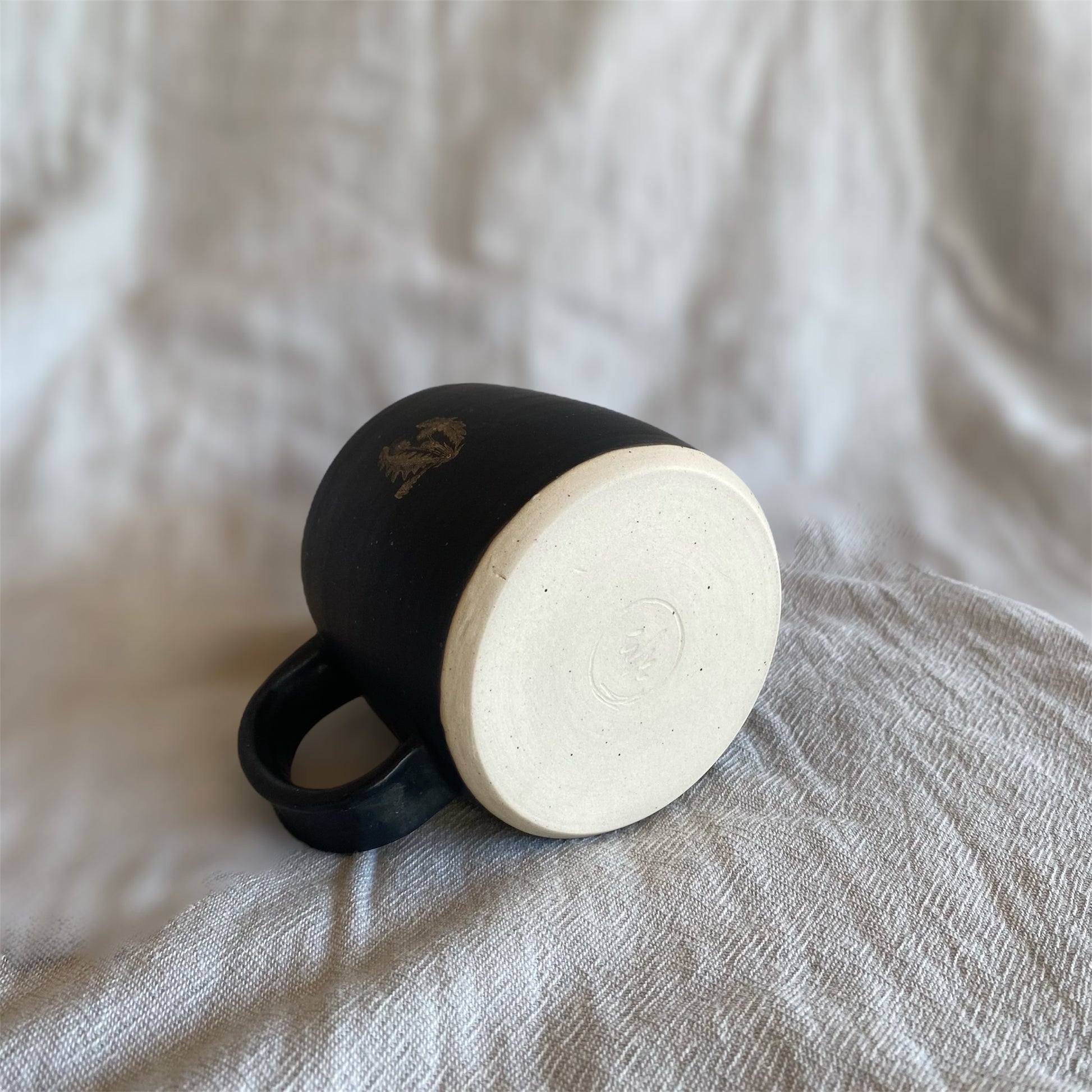 Black mug on a textured fabric surface