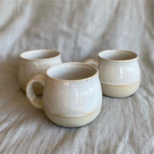 Three ceramic mugs on a textured beige surface