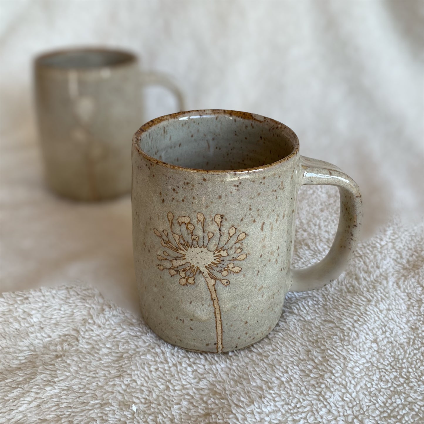 Ceramic mug with dandelion design on a textured surface