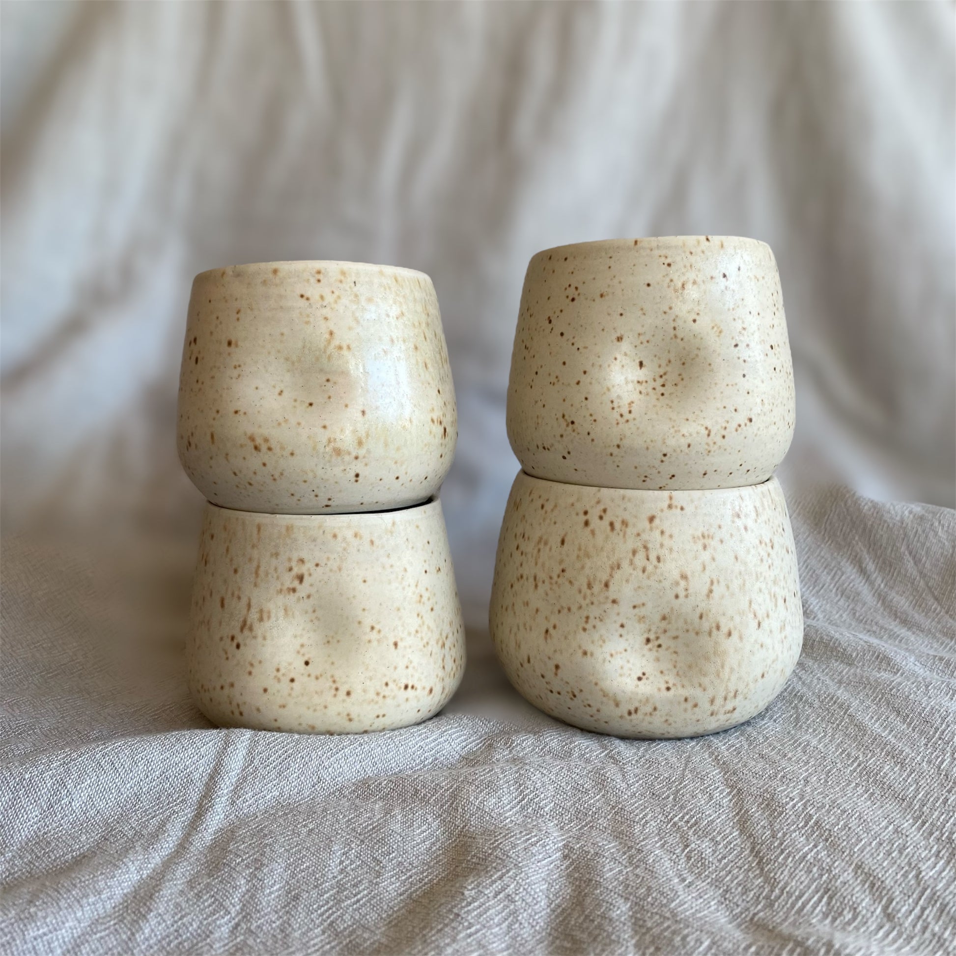 Four ceramic cups stacked on top of each other with a neutral background