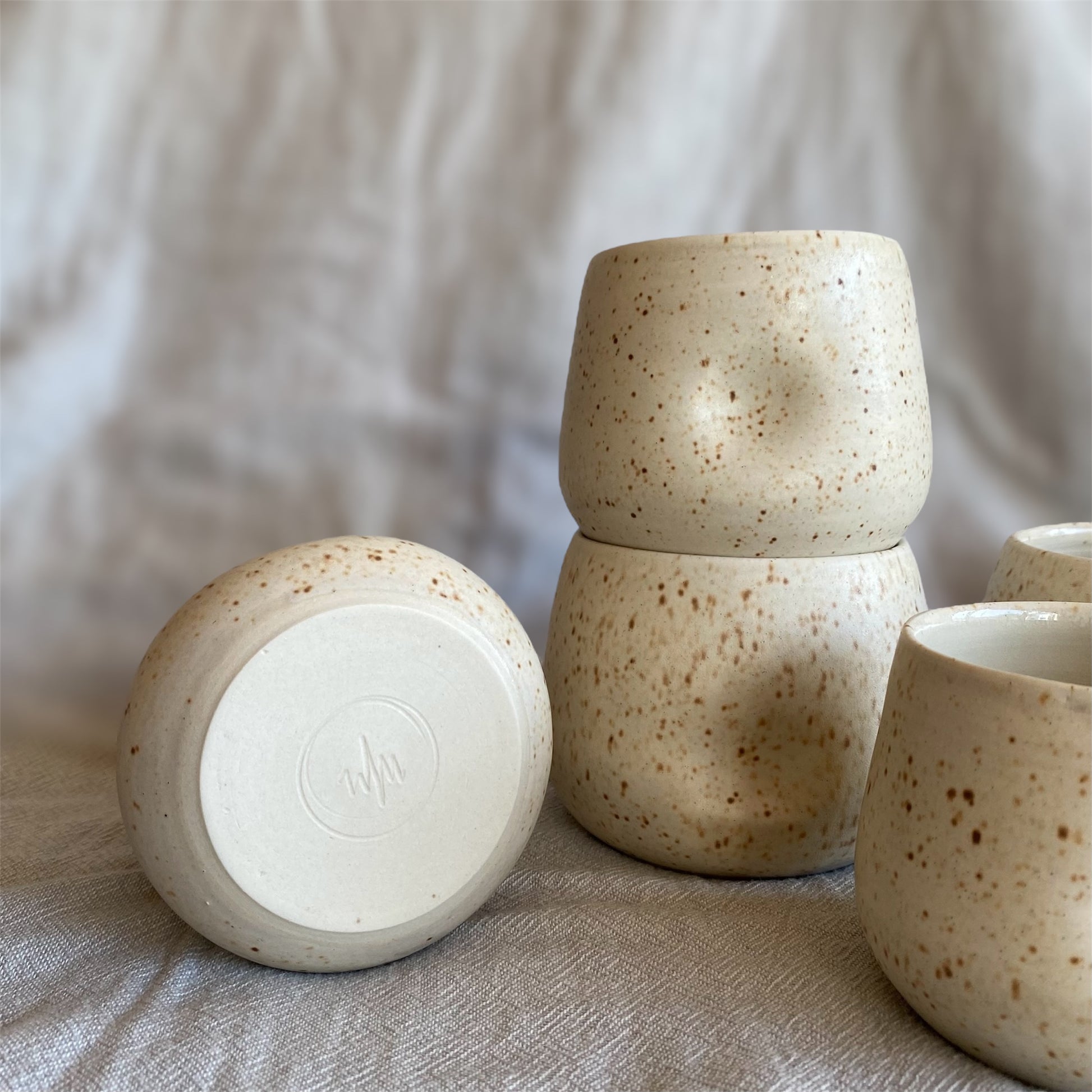Set of ceramic cups with speckled texture on a neutral background