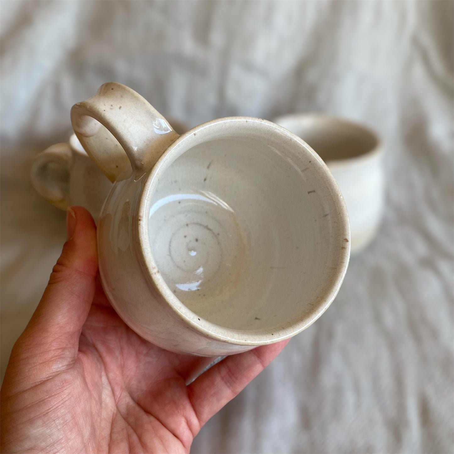 Hand holding a ceramic mug with a plain background