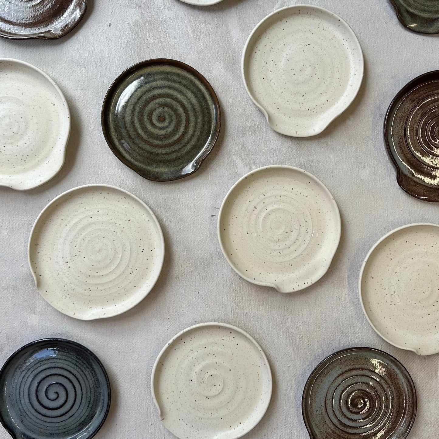 Collection of ceramic plates with spiral patterns on a gray surface