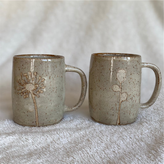 Two ceramic mugs with floral designs on a textured surface