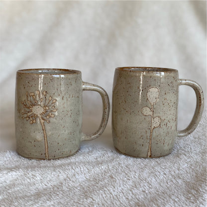 Two ceramic mugs with floral designs on a textured surface