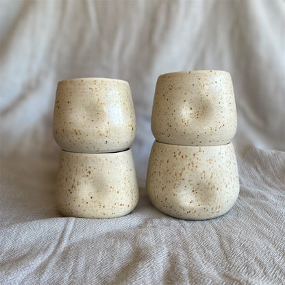 Four ceramic cups stacked on top of each other with a neutral background