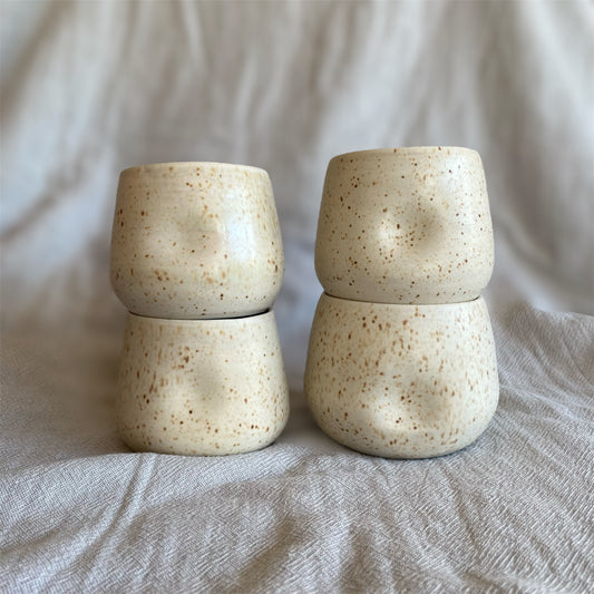 Four ceramic cups stacked on top of each other with a neutral background