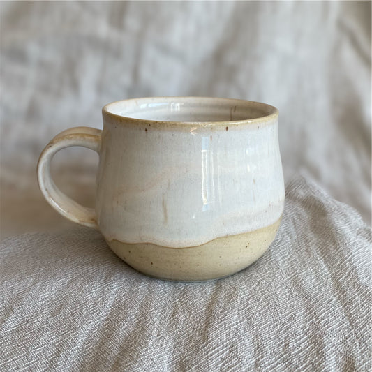 White ceramic mug with brown accents on a textured beige surface